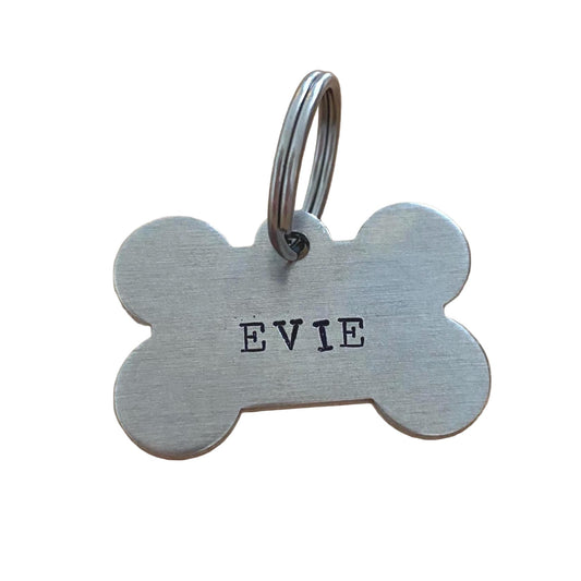 Aluminium dog tag shaped like a bone with 'EVIE' hand stamped on it.