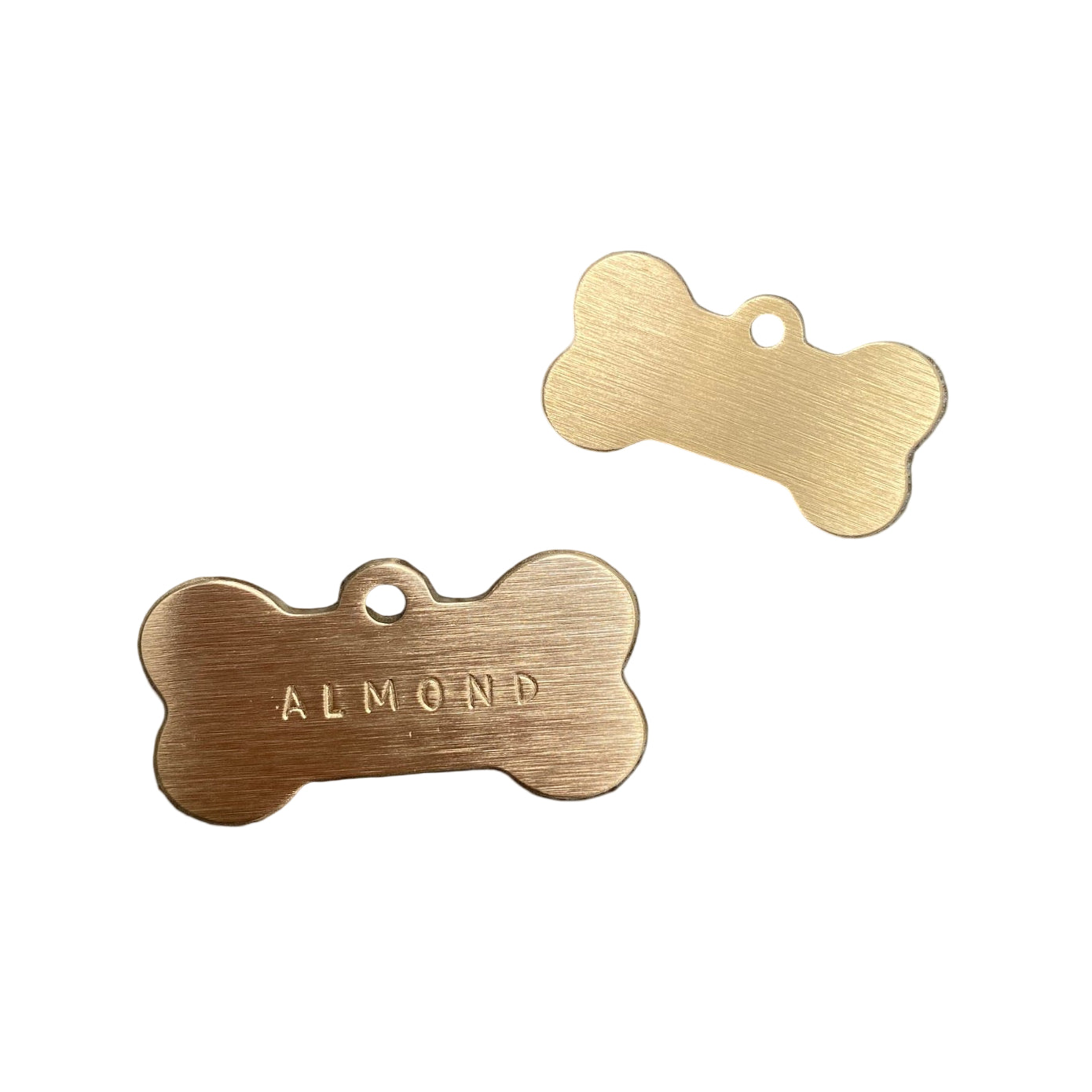 Two gold bone-shaped dog tags on a black background