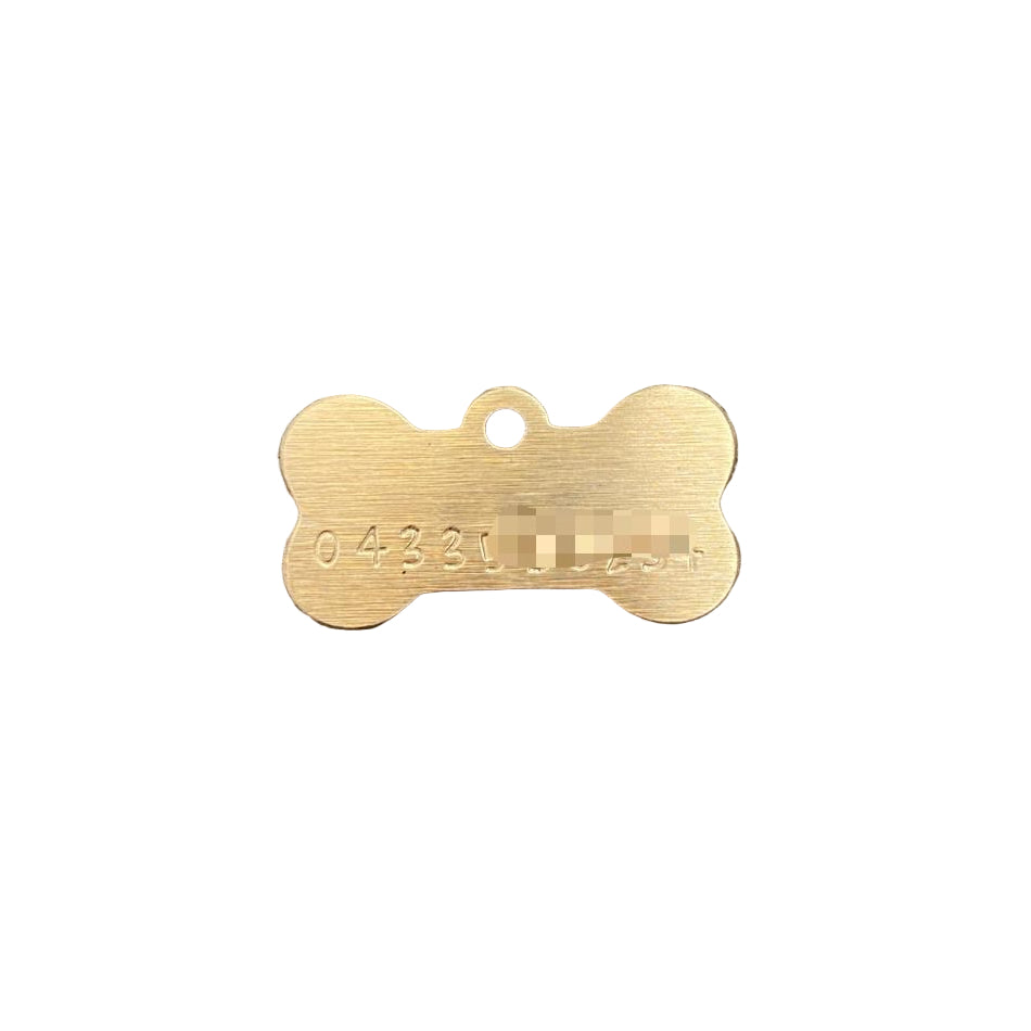 Gold bone-shaped dog tag on a white background